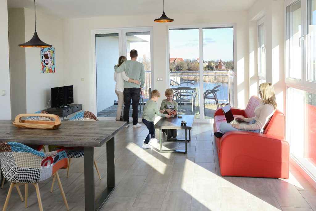 Familie im Wohnzimmer einer Ferienwohnung der Havel-Spitze mit Blick auf die Havel